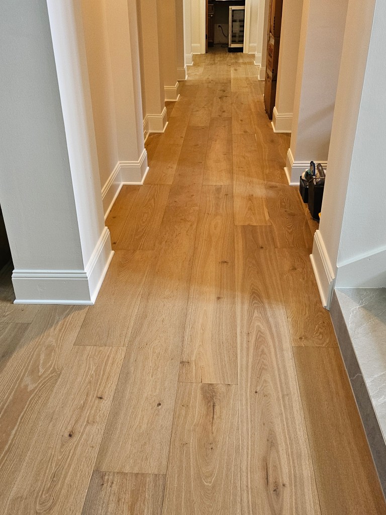 Engineered glue-down wood flooring installed down a long hallway by Advanced Flooring Removal