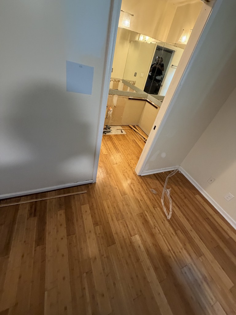 Glued-down hardwood floor in a hallway before removal
